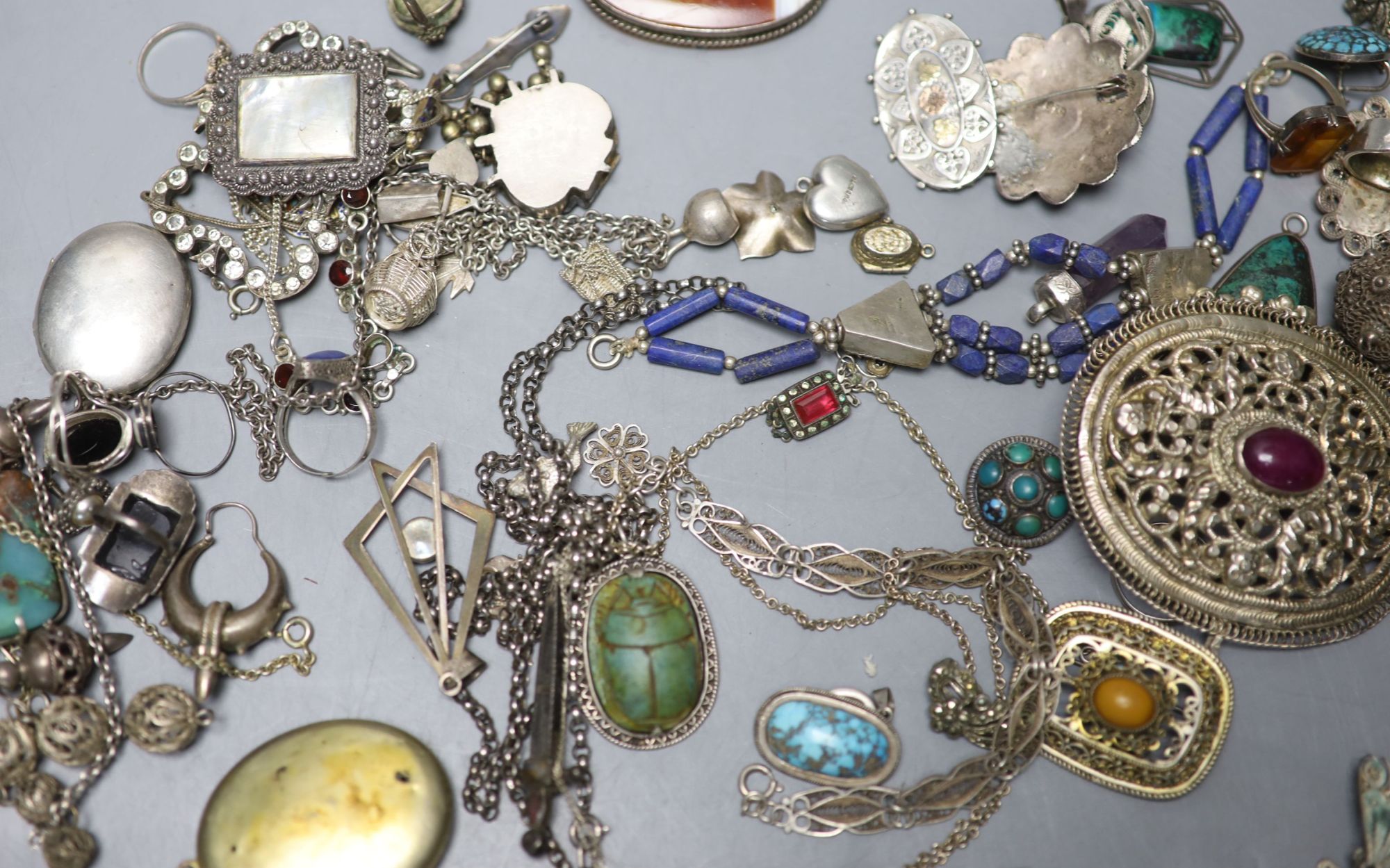 A mixed group of assorted white metal and costume jewellery including locket, brooches and filligree items.